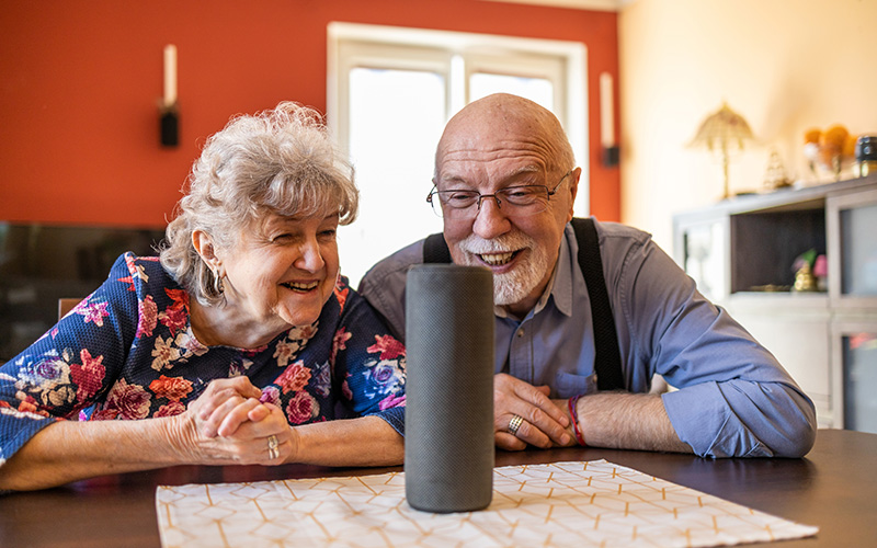 Excited senior couple using a Virtual Assistant at home