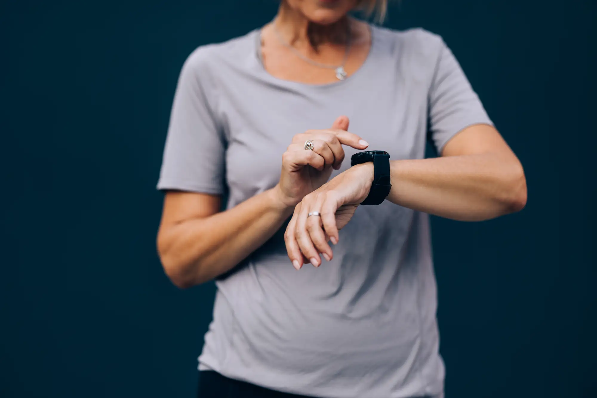 Hands of an unrecognizable woman runner checking her time on a smartwatch after exercising.