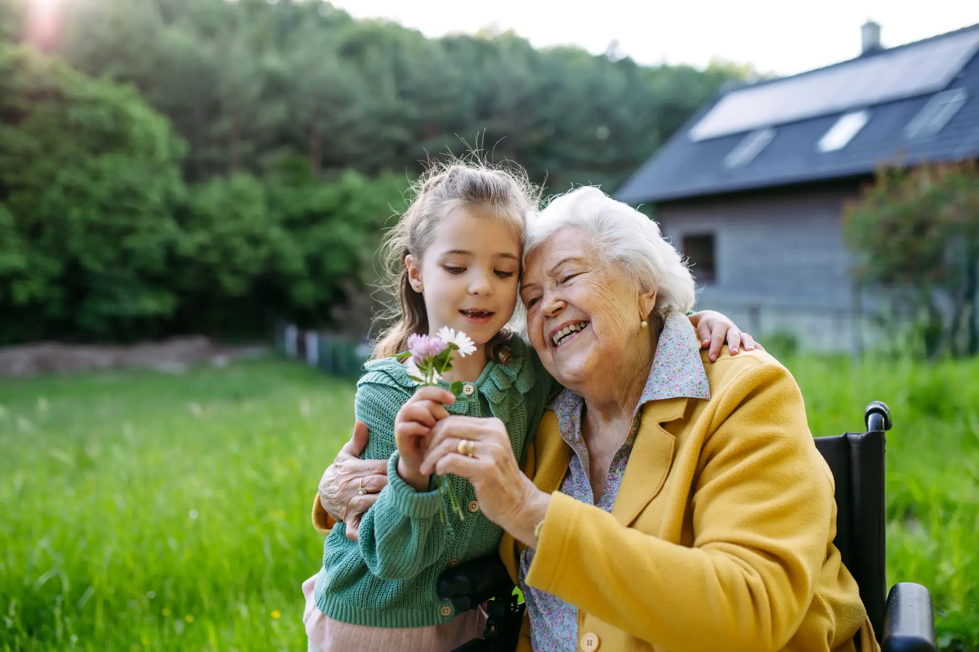 senior grandmother with granddaughter outside, admiring flower
