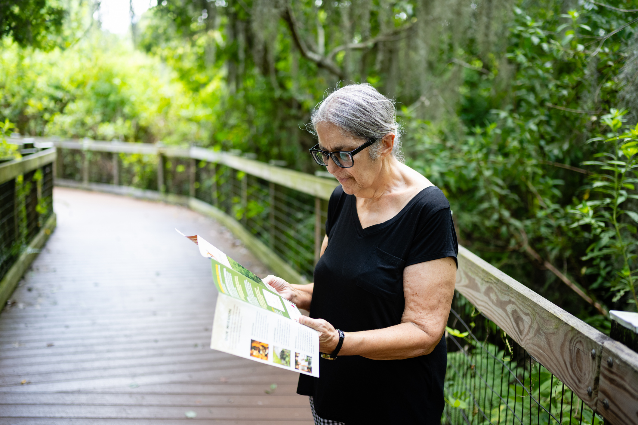 Senior Woman Reading Trail Map in Nature Reserve While Enjoying a Day Trip for Seniors